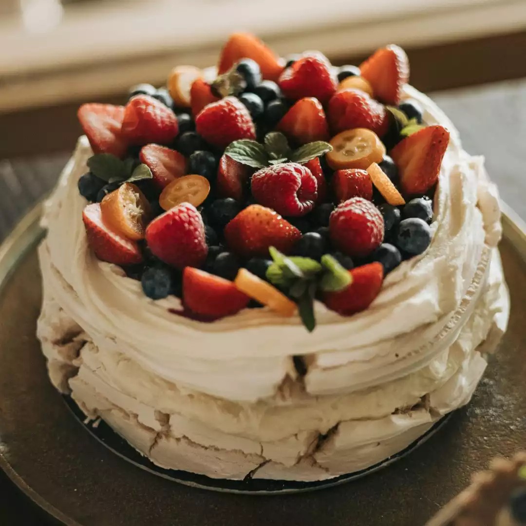 Beza Pavlova udekorowana świeżymi owocami, podana na eleganckim talerzu